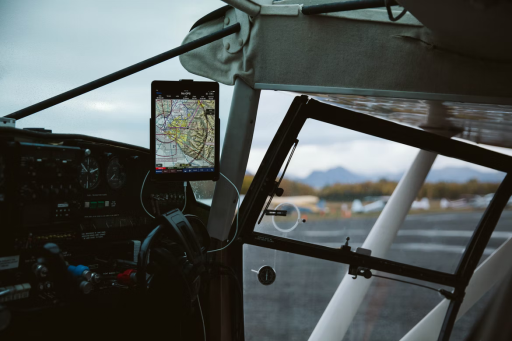 A GPS system mounted on a holder in an airplane sitting on tarmac.