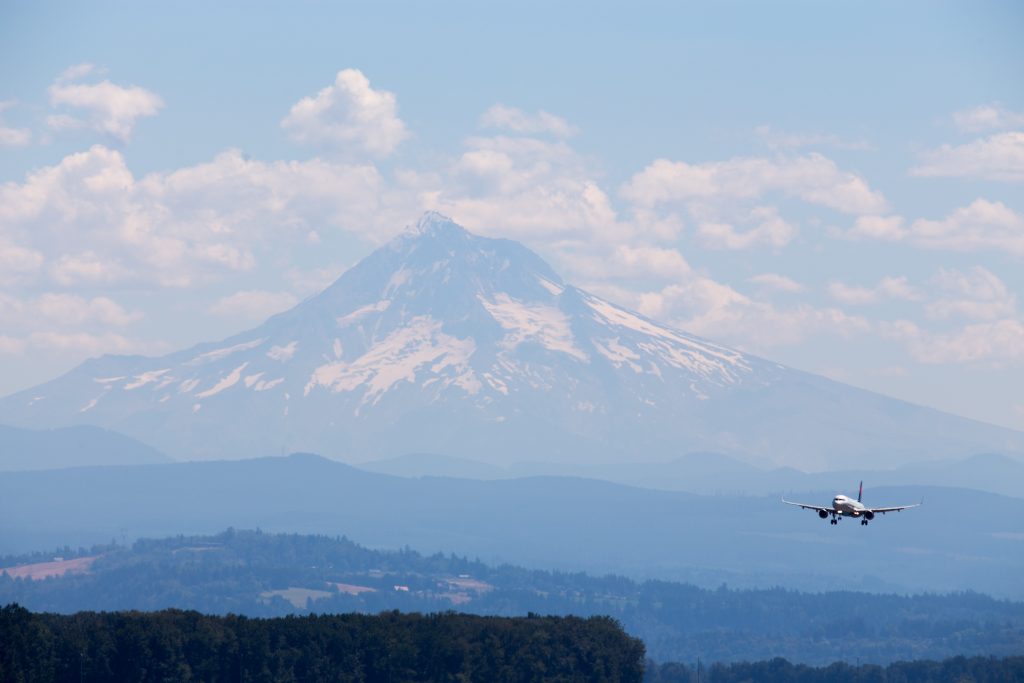 An airplane flying through a class B airspace in a mountainous region on a cloudy day. 