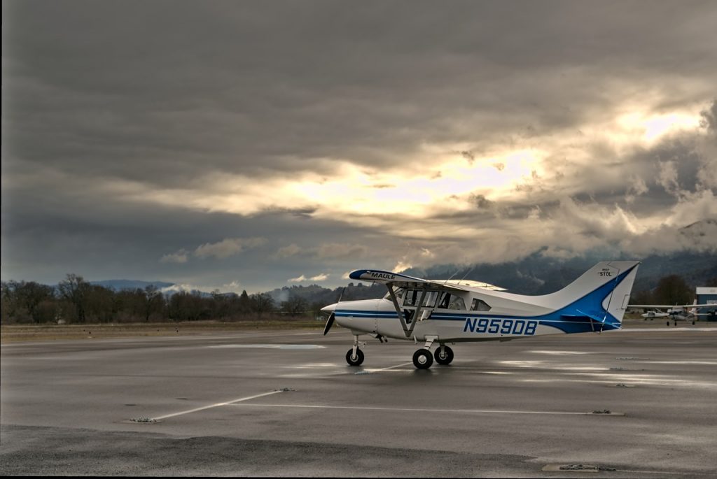 A small aircraft parked on the tarmac in an airfield in the evening.