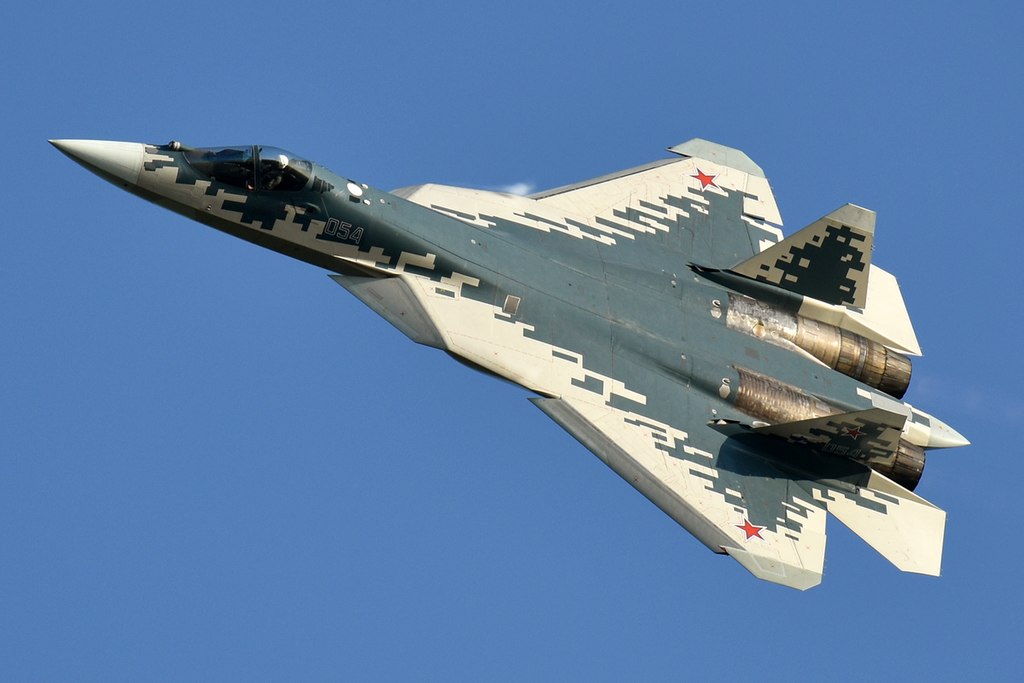 Sukhoi Su-57 in flight across a blue sky.