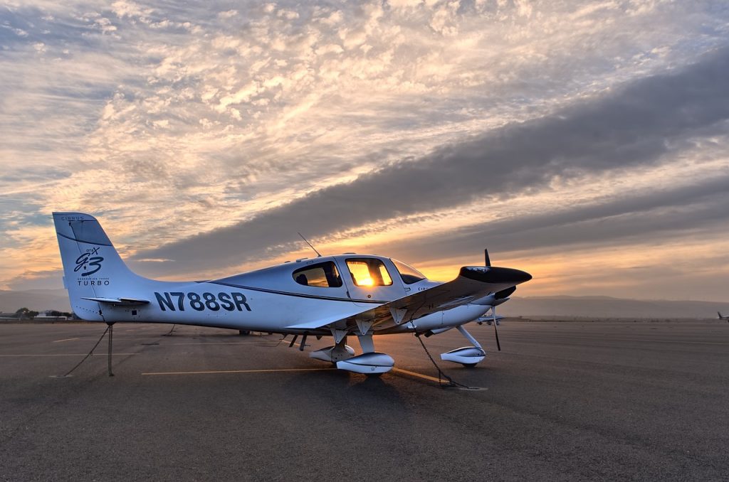 Cirrus SR22 aircraft stationed on a tarmac in an airfield in the evening.