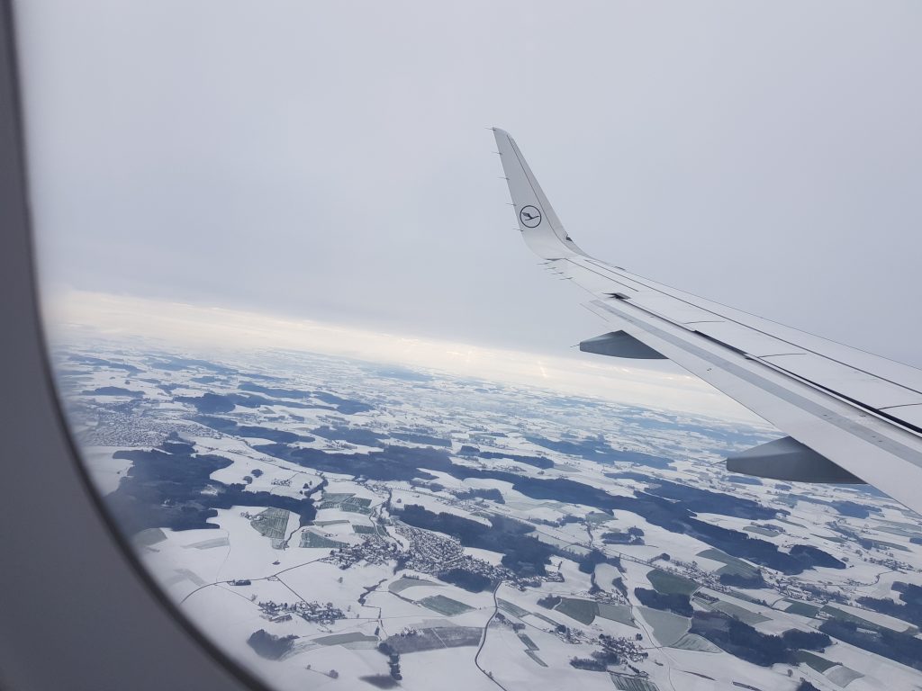 An airplane flying over snowy fields in Germany. 
