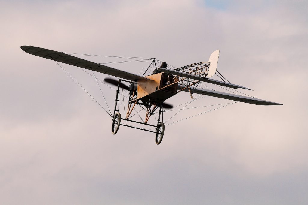 An old-fashioned airplane controlled by one pilot flying in the sky.