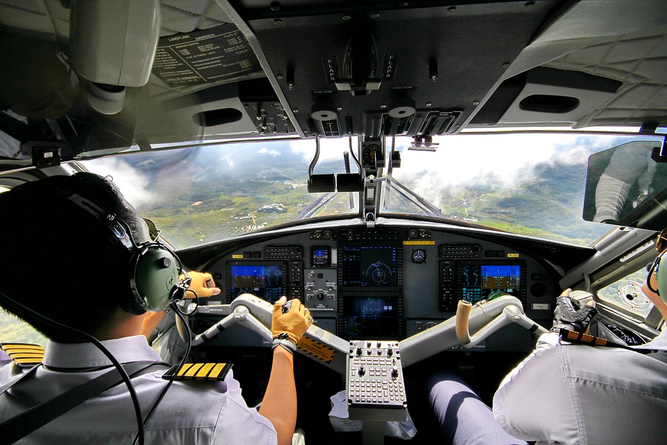 Two pilots in a cockpit preparing to land the plane. 