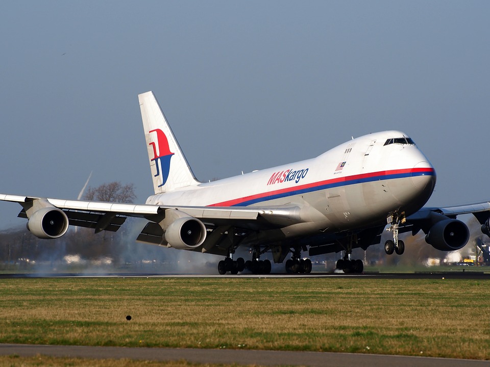 Boeing 747 delivering air cargo and landing at an airport in daytime. 