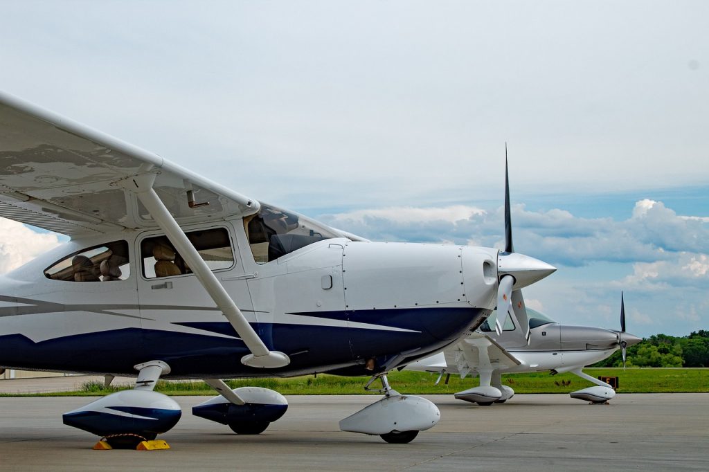 Two Cirrus SR22 aircrafts stationed on a runway on a cloudy summer day.