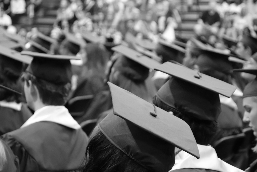 University graduates attending a ceremony wearing black robes and graduation caps.