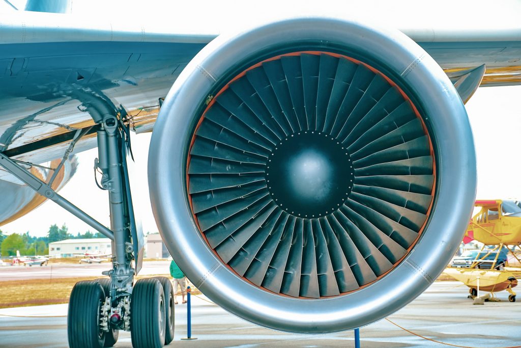 A central view of an aircraft engine attached to the wing of an airplane.