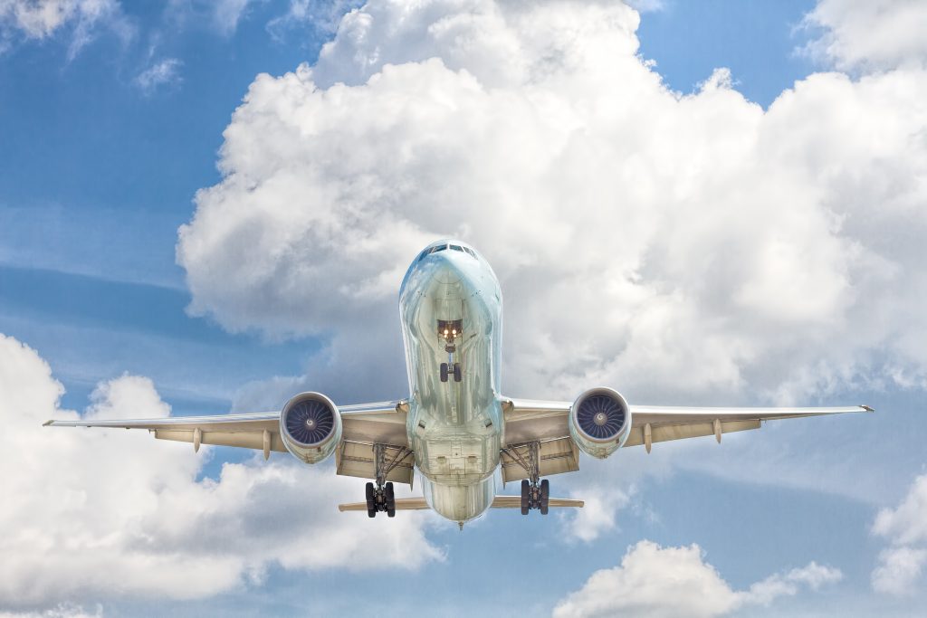 A view of an airplane from below in a slightly cloudy sky.