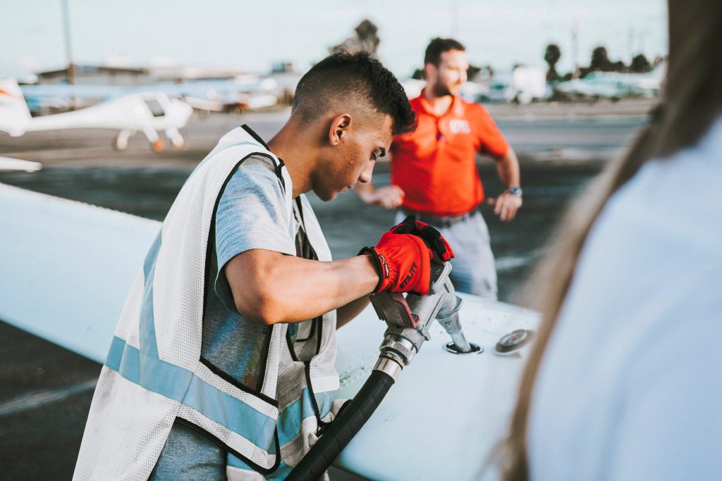 An airport worker refueling a small aircraft. 