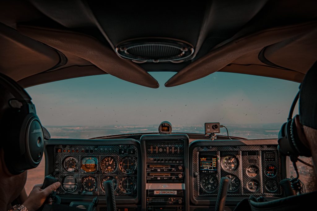 Two pilots navigating a plane in their cockpit in the evening. 