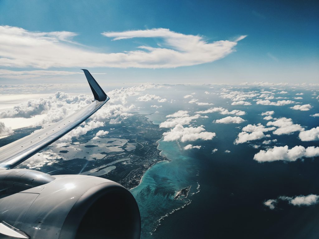 A view of an aircraft's wing and engine while flying over a coast.