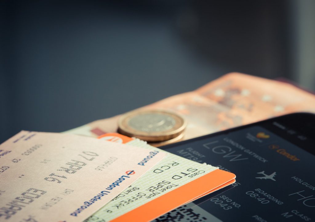 Paper and electronic boarding passes for a flight an some Euros on a table.