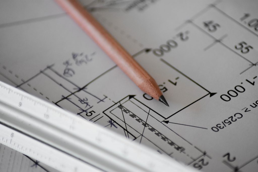 A paper with calculations and designs with a pencil and a ruler placed on it. 