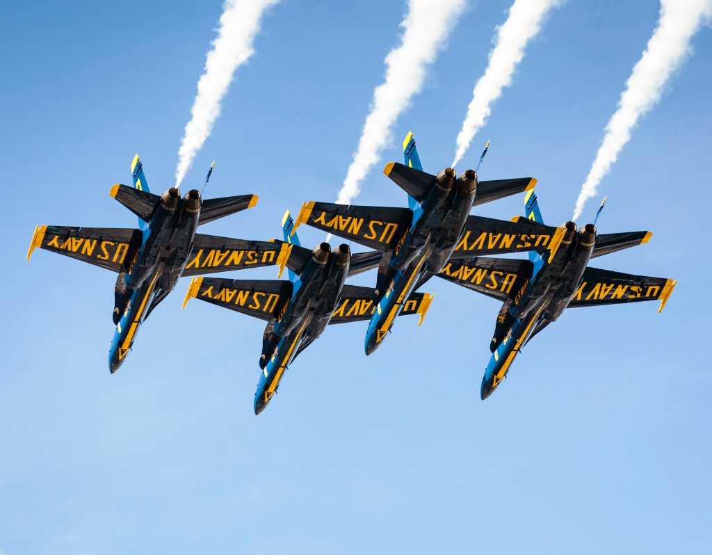 US Navy F18's flying in a formation, all equipped with white smoke oil.