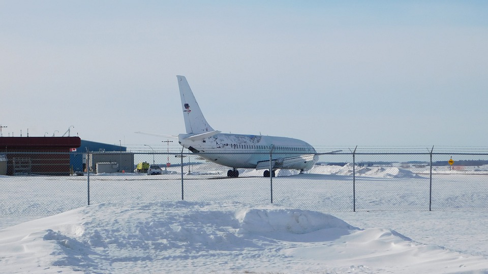An aircraft parked in a snowy airport during the day.