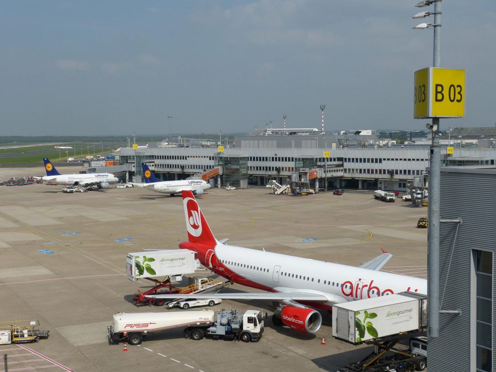 An airplane being loaded and tanked with jet fuel at airport gates B03 on a clear day