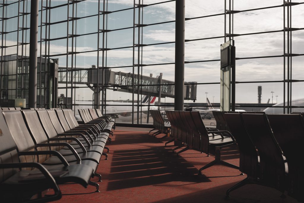 A clean, near and well-lit airport terminal waiting hall with a jet way visible through the windows.