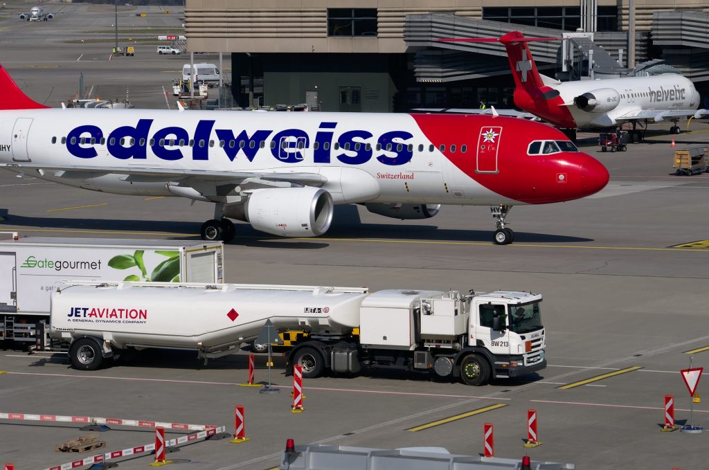 A view of an aircraft and a jet fuel tank standing next to each other at an airport.