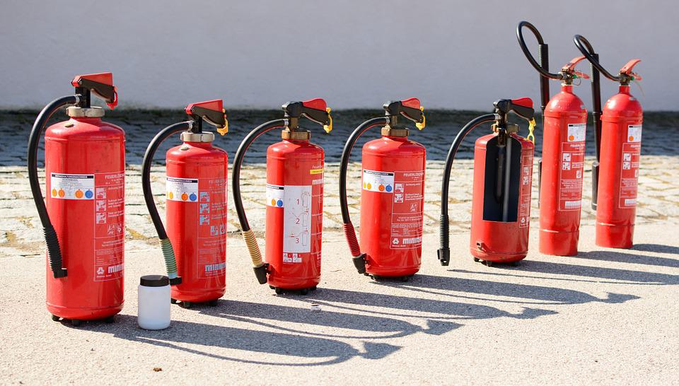 Various types of fire extinguishers on displayed outside a building. 