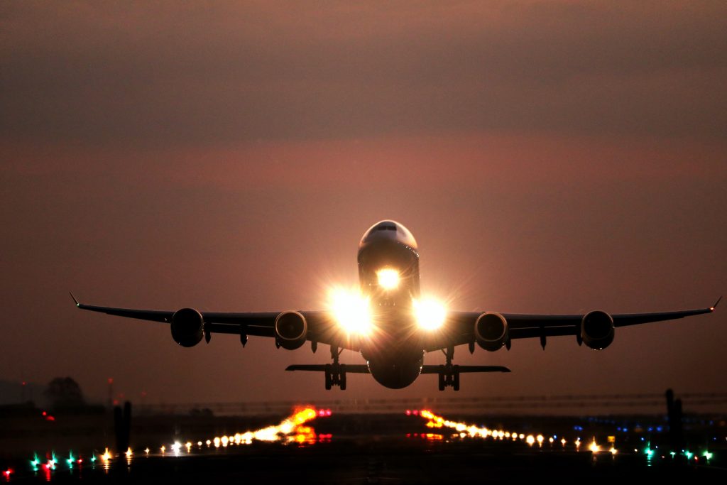 An aircraft landing over a well-illuminated runway at night.