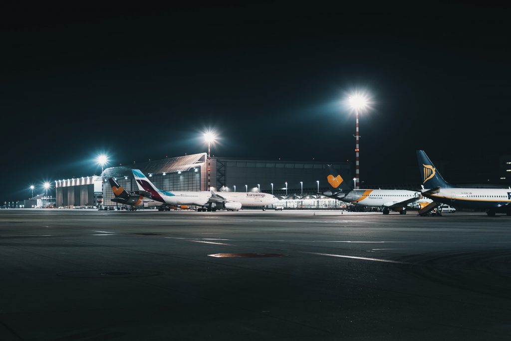 Aircraft stationed on the taxiway illuminated by bright lights at night.