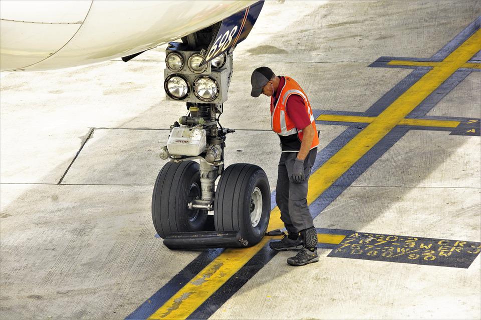 An aircraft engineer inspecting the landing gear of an aircraft. 