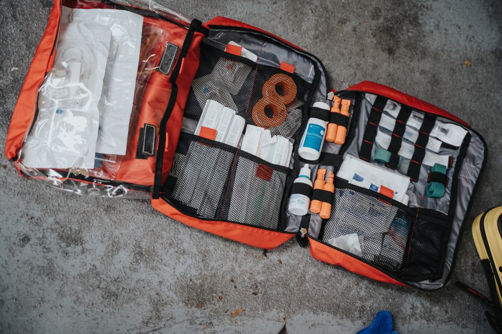 A first-aid kit box opened on a concrete floor.