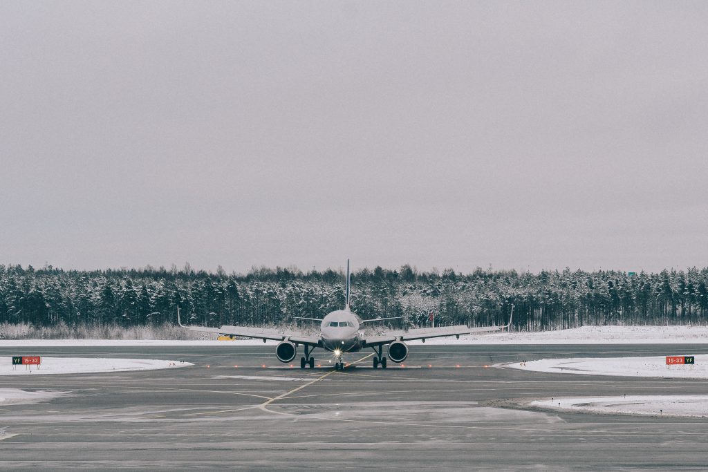 An airplane taxiing through a snowy airport on a cloudy winter day.