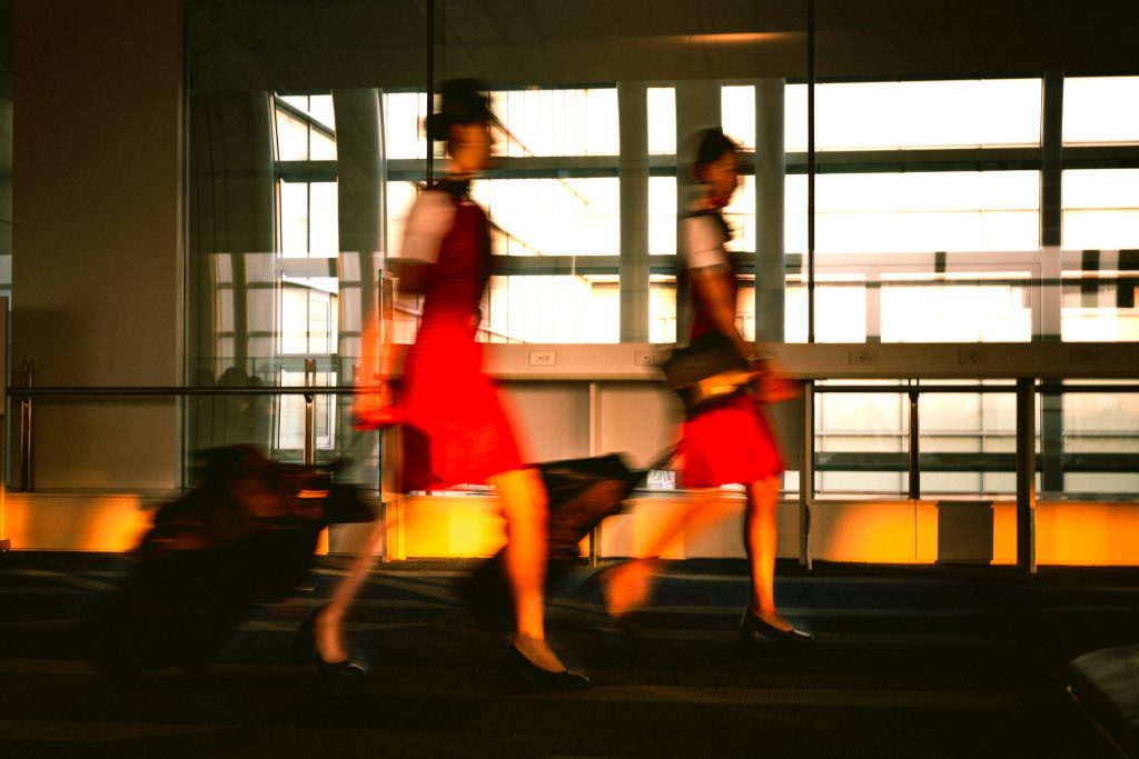 Two flight attendants walking down a terminal building at an airport.