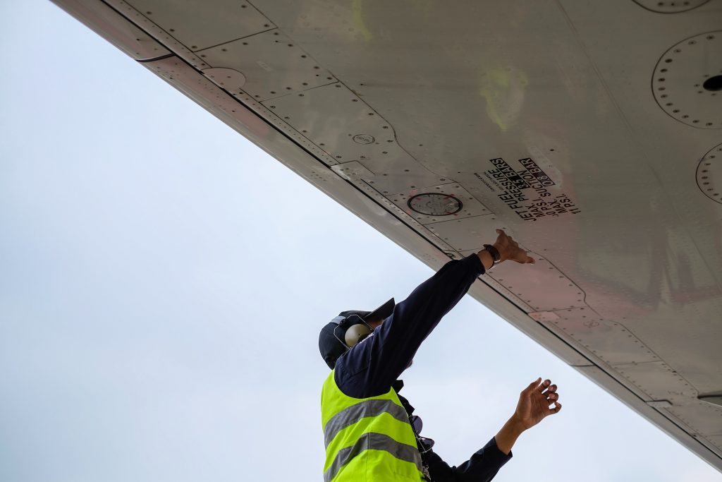 An aircraft technician performing maintenance work on an aircraft wing.