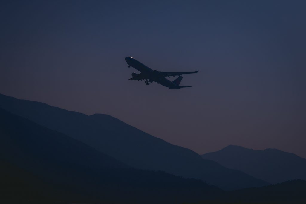 An aircraft taking off at night over mountains. 