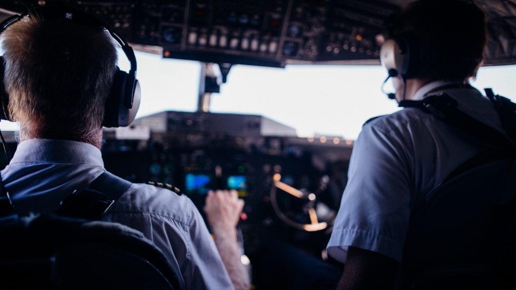 Two airline pilots sitting in a cockpit of an aircraft preparing for a flight. 