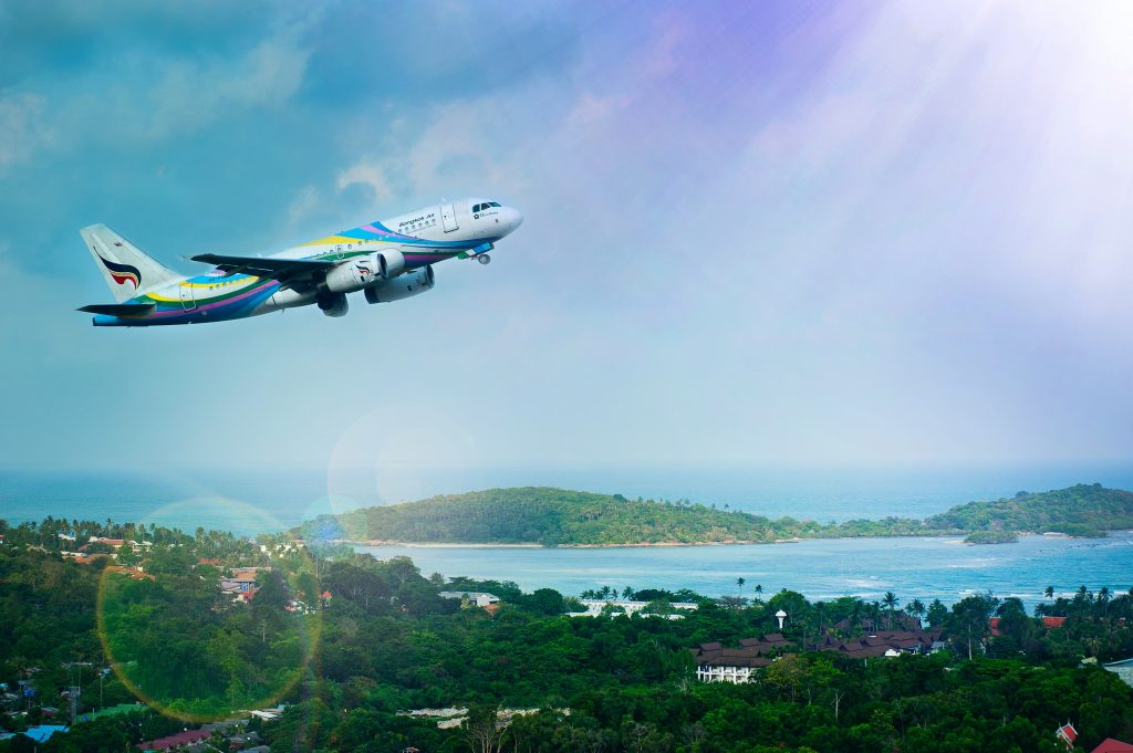 A passenger aircraft flying over a bay on a hot summer day. 