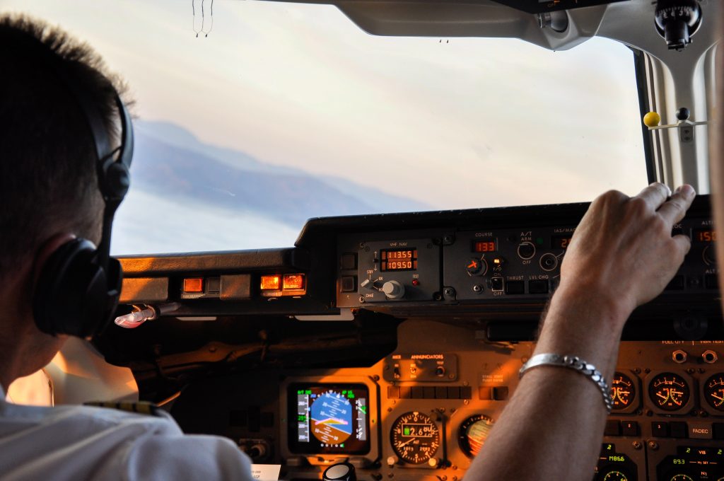 A pilot of an aircraft performing a maneuver over a mountainous terrain. 