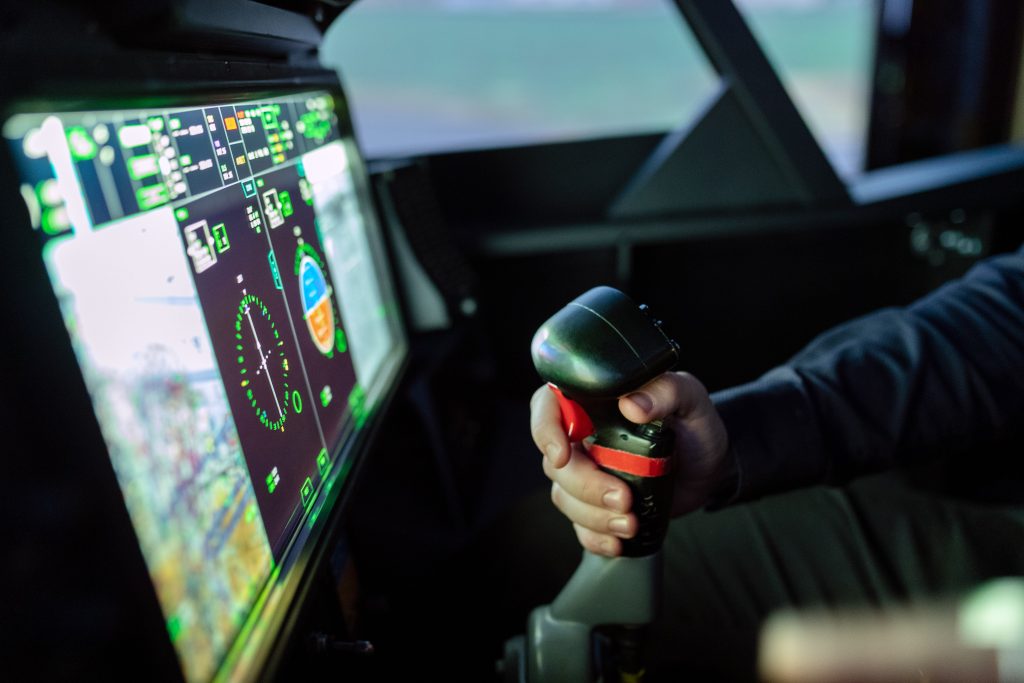 A person in a flight simulator learning to fly, holding onto the control column.