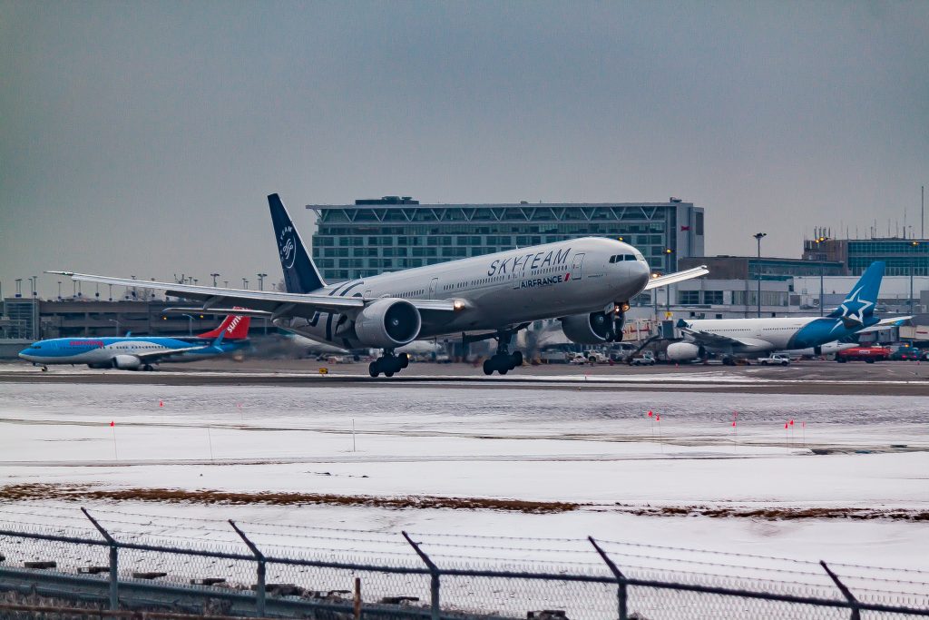 An Air France aircraft taking off on a runway near an airport terminal building on a winter day.