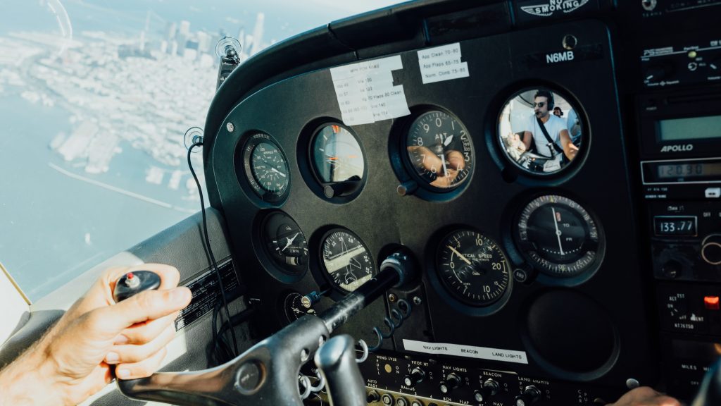 A private pilot controlling a small aircraft and carrying a passenger in the back.