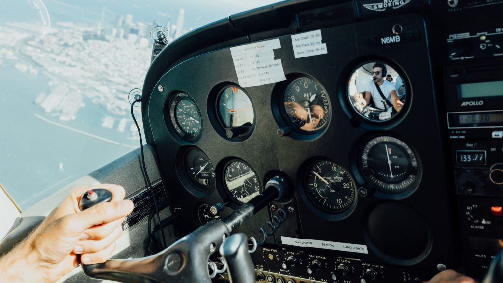 A person piloting a small aircraft over a large city on the coast.