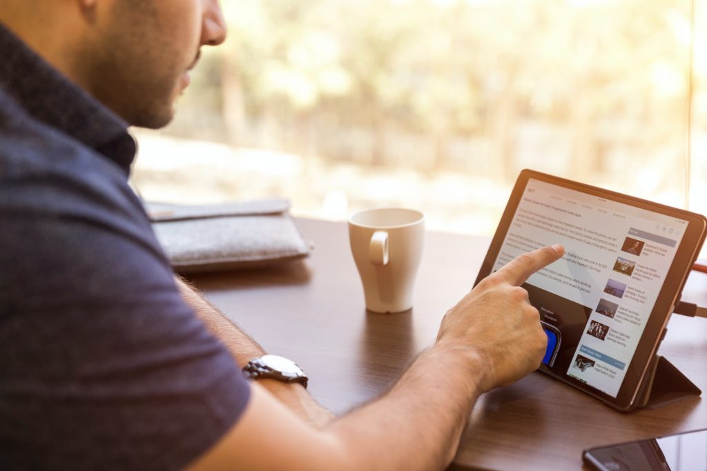 A man in a blue T-shirt browsing Linkedin Learning courses on his tablet.