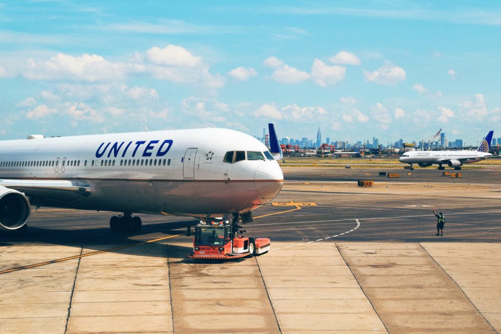 A United Airlines jetliner being towed to the taxiway on a clear day. 