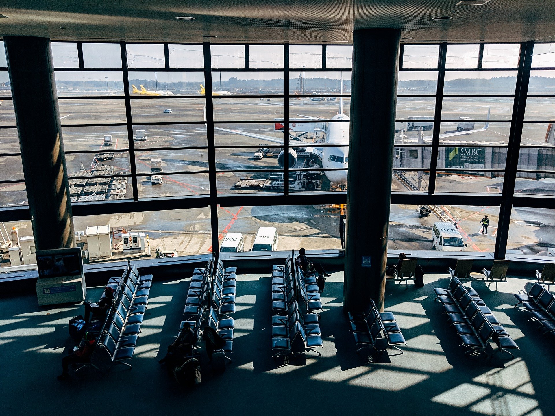 Tokyo Haneda airport waiting hall and an aircraft parked at a jetway on a clear day.