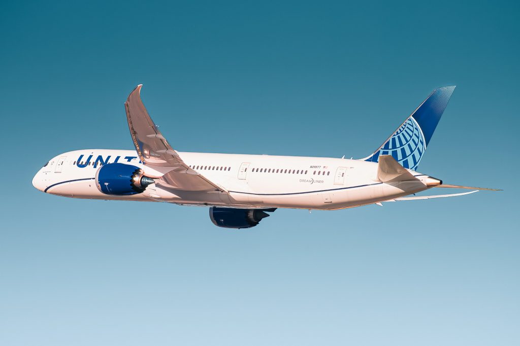 A United airlines Boeing 787 Dreamliner in flight across the blue sky. 