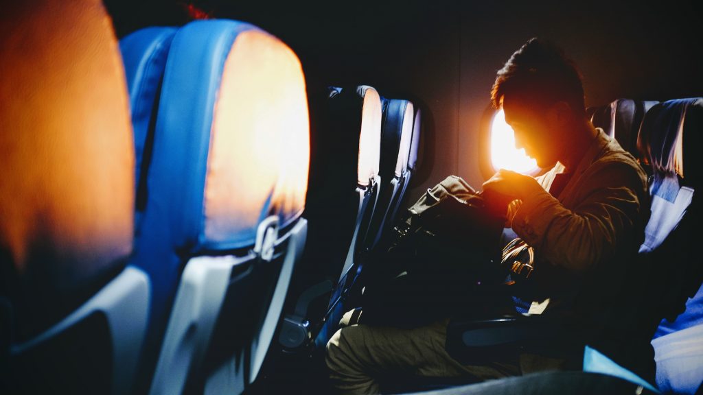 A person sitting in an aircraft where a sun is shining through the window. 