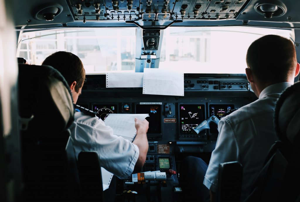 Two pilots in a cockpit of an aircraft are going through a pre-flight checklist together.
