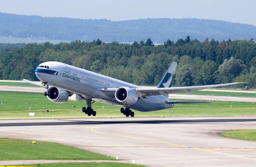 A Cathay Pacific Boeing 777 taking off from the runway on a clear day. 