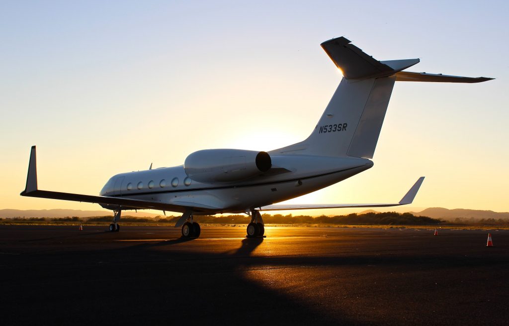 A private civil airplane parked on tarmac in sunset. 