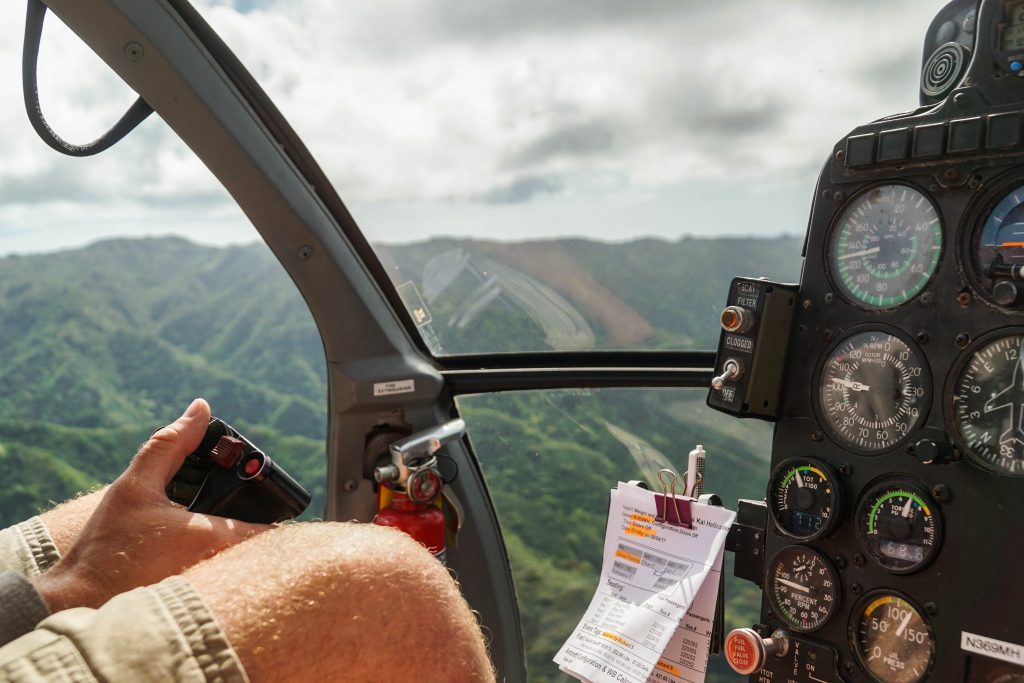 A helicopter pilot in a cockpit with a flight checklist attached in a cockpit. 