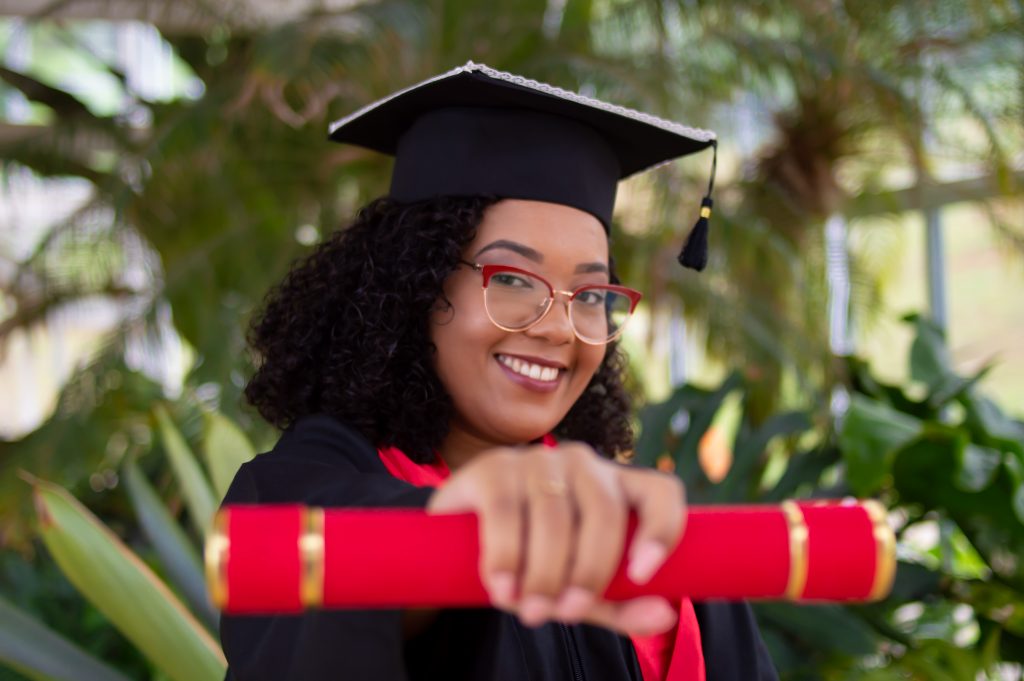 A university for aviation graduate wearing a graduation cap and a robe, showing off her university diploma. 