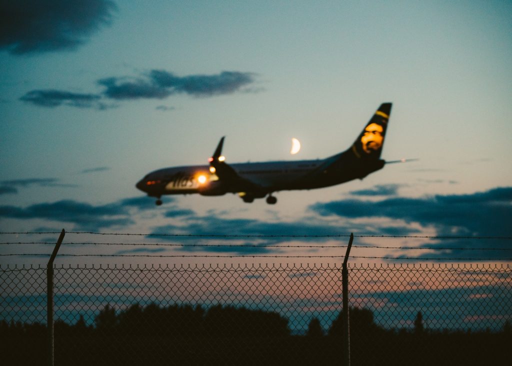 An aircraft with landing lights on is landing at night on a runway.